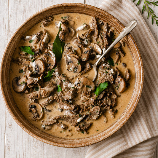 Beef stroganoff in a bowl with a spoon on a wooden surface