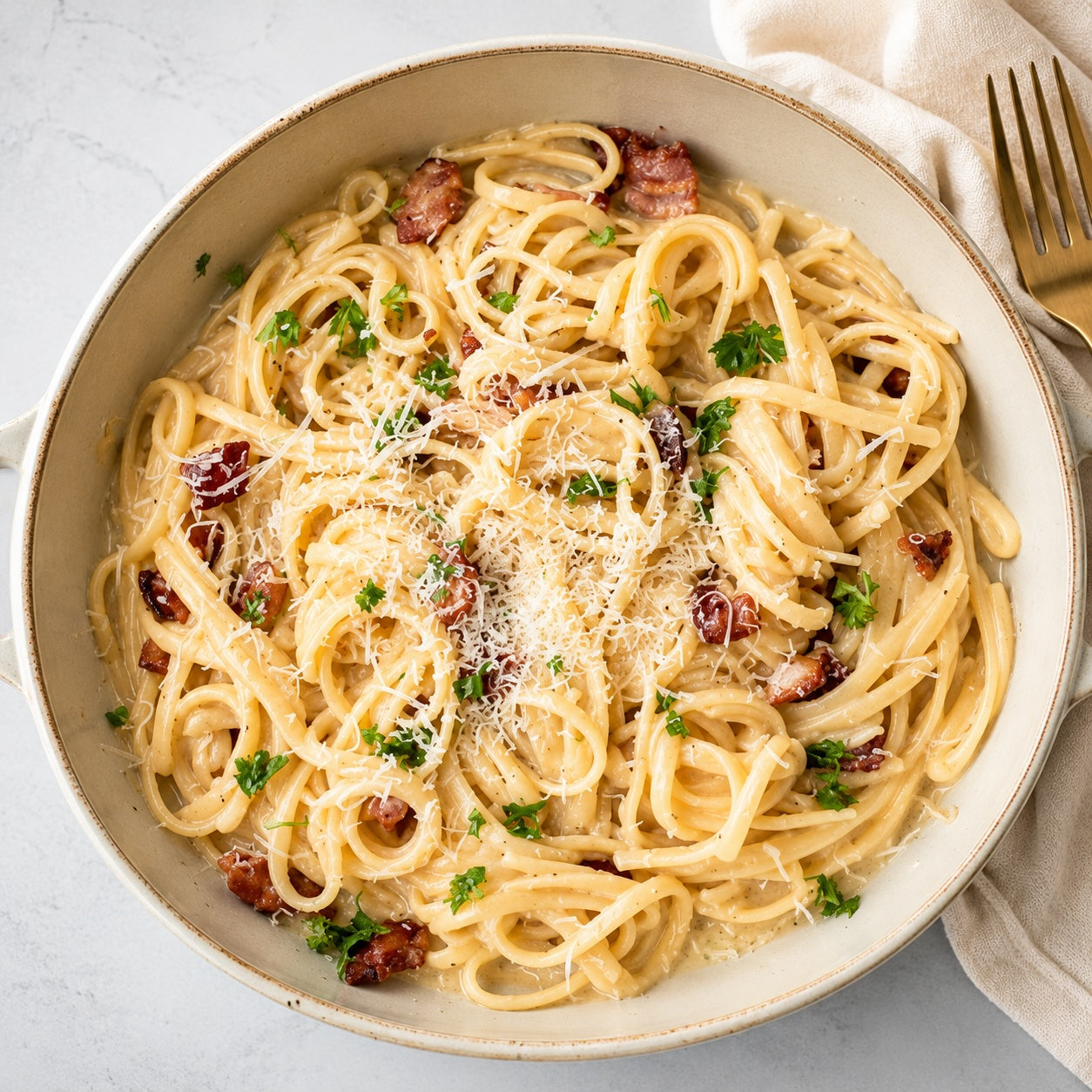 Spaghetti dish with bacon and herbs in a bowl on a light background