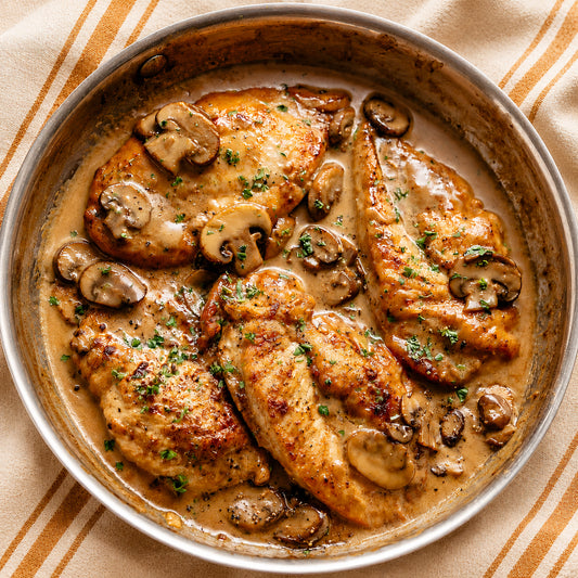 Chicken Marsala dish in a pan on a striped tablecloth