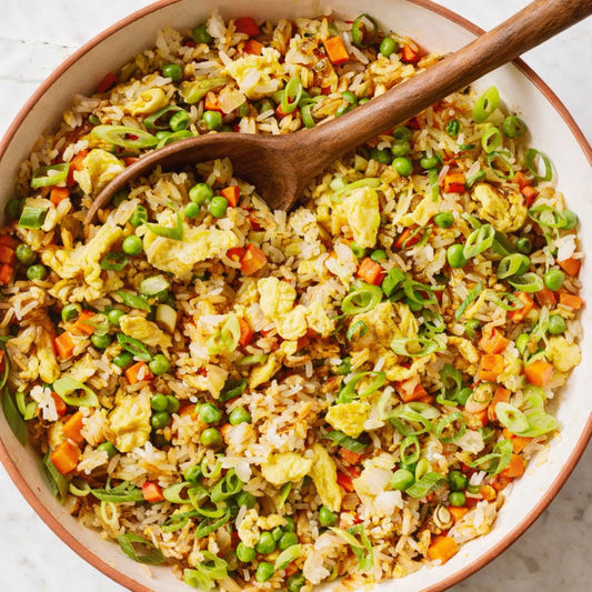Fried rice with vegetables in a bowl with a wooden spoon