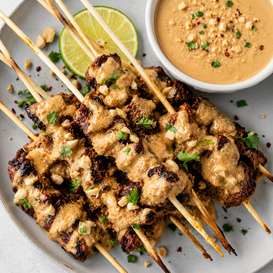 Skewers of grilled chicken with peanut sauce on a plate